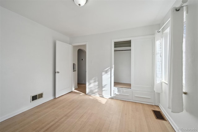 unfurnished bedroom featuring multiple windows, light hardwood / wood-style floors, and a closet