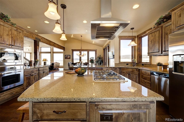 kitchen featuring island exhaust hood, stainless steel appliances, decorative light fixtures, light stone countertops, and a center island