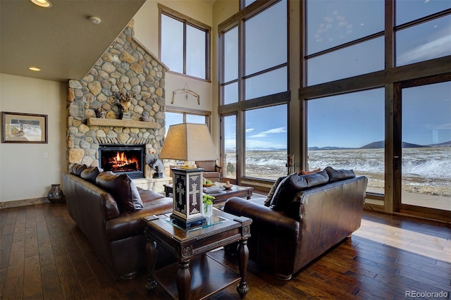 living room featuring dark wood-type flooring, a fireplace, and a towering ceiling