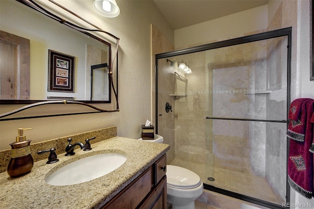 bathroom with toilet, a shower with door, and vanity