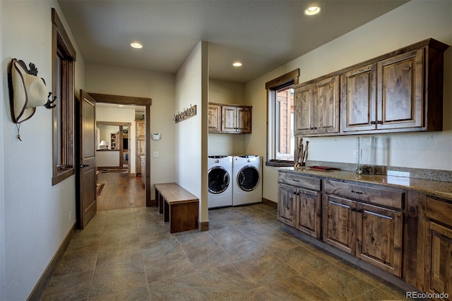 clothes washing area with washing machine and dryer and cabinets