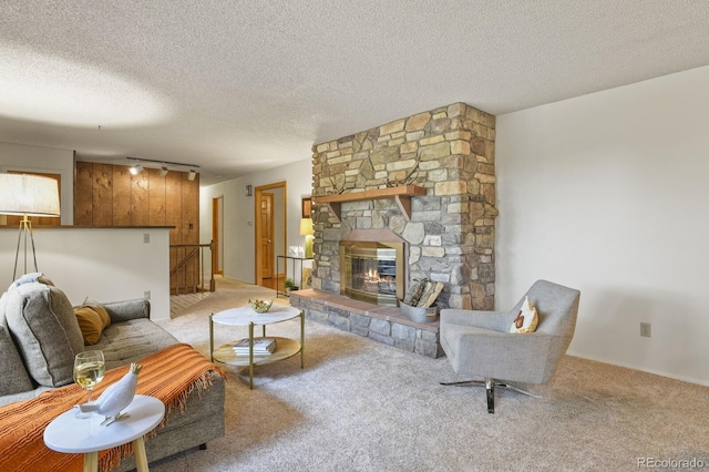 living room with carpet floors, a textured ceiling, track lighting, and a fireplace