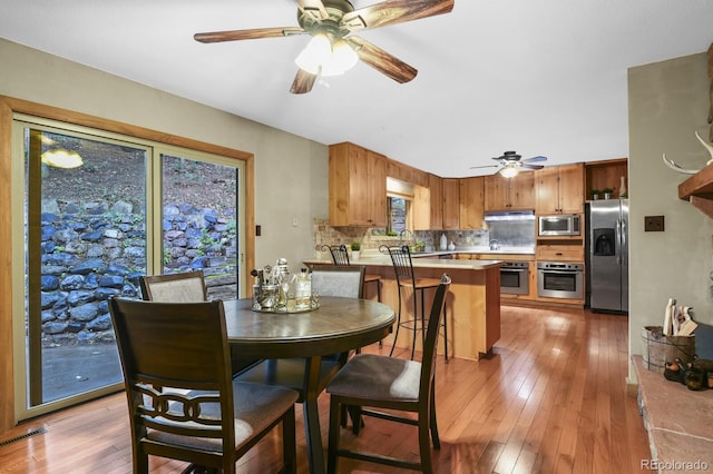 dining room featuring visible vents, light wood-style floors, and ceiling fan