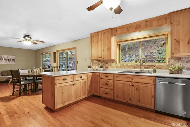 kitchen featuring a sink, stainless steel dishwasher, a peninsula, and light countertops