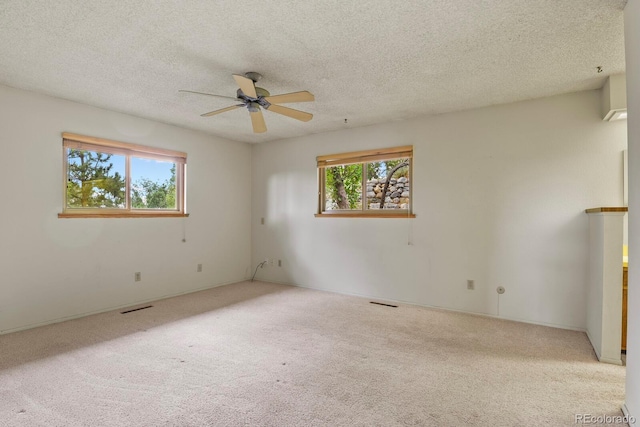 carpeted empty room with plenty of natural light, visible vents, and a textured ceiling