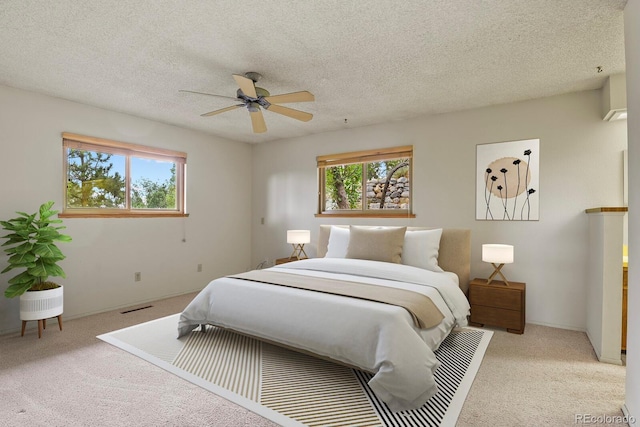 bedroom with multiple windows, carpet, visible vents, and a textured ceiling