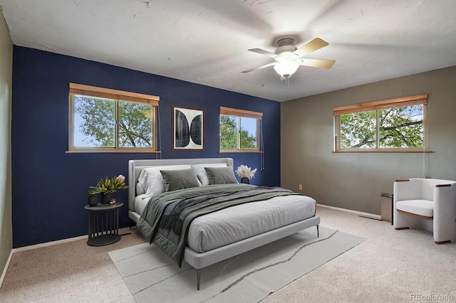 carpeted bedroom with multiple windows, baseboards, and ceiling fan