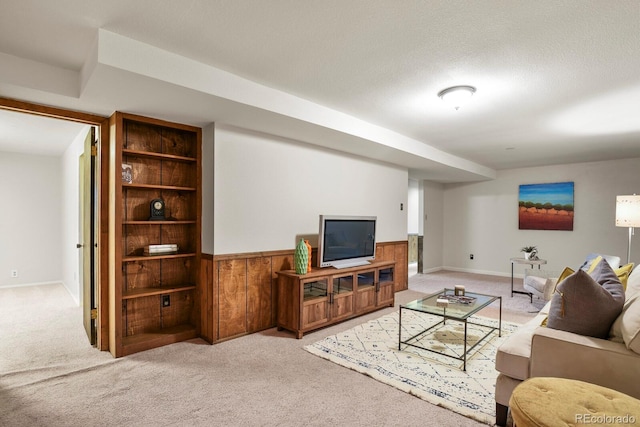 carpeted living room featuring wainscoting, a textured ceiling, and wood walls