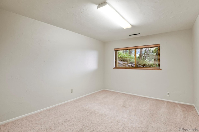 carpeted spare room featuring visible vents and baseboards