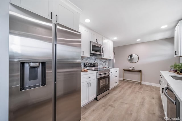 7150 Beach St, Westminster, CO 80030 - kitchen featuring appliances with stainless steel finishes, light countertops, white cabinets, backsplash, and light wood-style floors
