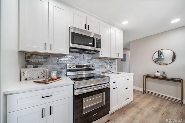 7150 Beach St, Westminster, CO 80030 - kitchen with stainless steel appliances, tasteful backsplash, light countertops, white cabinetry, and light wood-style floors