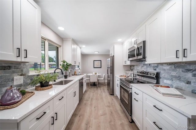 7150 Beach St, Westminster, CO 80030 - kitchen with appliances with stainless steel finishes, light wood-style floors, white cabinets, decorative backsplash, and recessed lighting