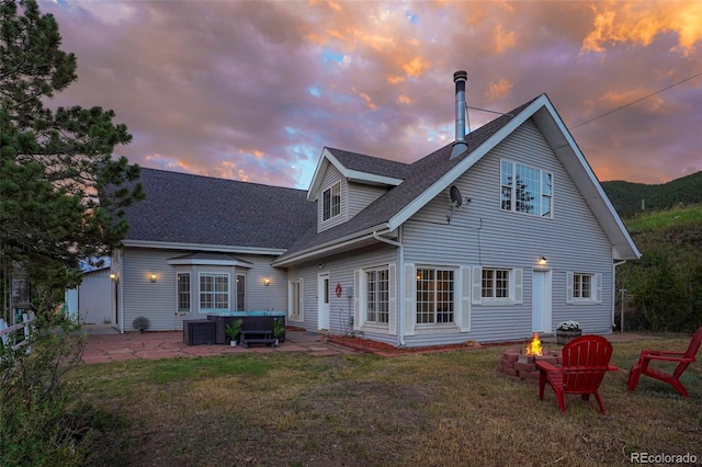 back house at dusk featuring a yard, a fire pit, and a patio area