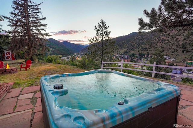 pool at dusk with an outdoor fire pit and a mountain view