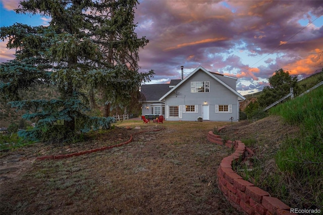 back house at dusk with a lawn