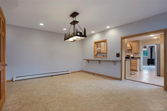 empty room featuring ceiling fan, a baseboard radiator, light tile patterned floors, and a wood stove