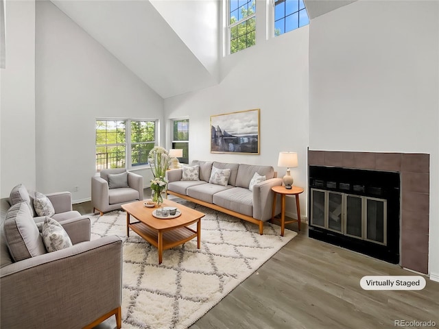 living room with a high ceiling, healthy amount of natural light, wood finished floors, and baseboards