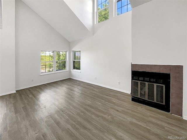 unfurnished living room featuring a high ceiling, plenty of natural light, wood finished floors, and baseboards