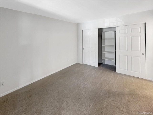 unfurnished bedroom with carpet flooring, baseboards, and a closet