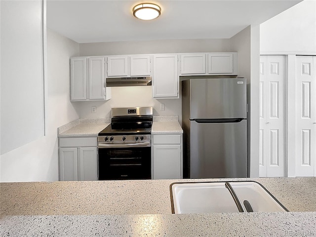 kitchen featuring stainless steel appliances, under cabinet range hood, a sink, light stone countertops, and white cabinets
