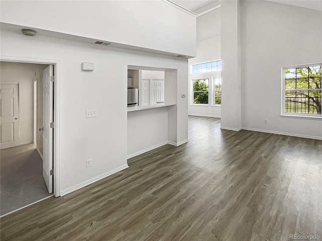 unfurnished living room featuring high vaulted ceiling, baseboards, and dark wood finished floors