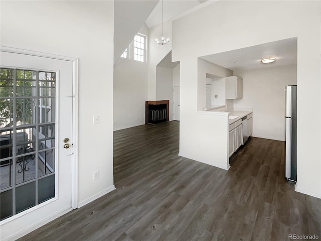 kitchen featuring stainless steel appliances, a chandelier, healthy amount of natural light, dark wood-style floors, and a towering ceiling