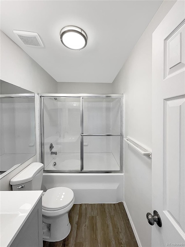 full bath with wood finished floors, vanity, combined bath / shower with glass door, and toilet