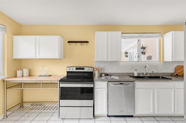 6535 Balsam St, Arvada, CO 80004 - kitchen with stainless steel appliances, a sink, white cabinetry, and light tile patterned floors
