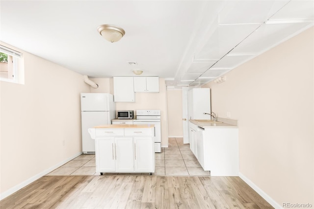 6535 Balsam St, Arvada, CO 80004 - kitchen with white appliances, light wood-style flooring, white cabinets, a kitchen island, and a sink