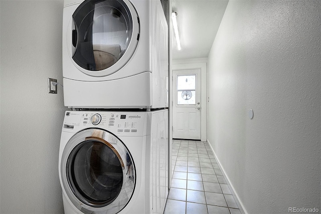 11669 S Upper Ranch Dr, Pine, CO 80470 - laundry area featuring stacked washer and clothes dryer, light tile patterned flooring, baseboards, and a textured wall