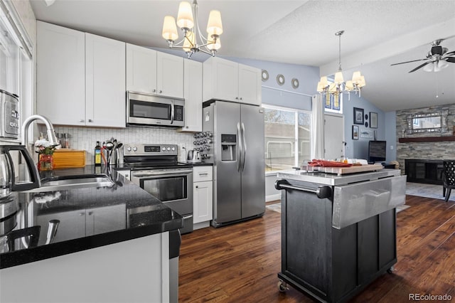 kitchen with backsplash, sink, vaulted ceiling, appliances with stainless steel finishes, and white cabinetry