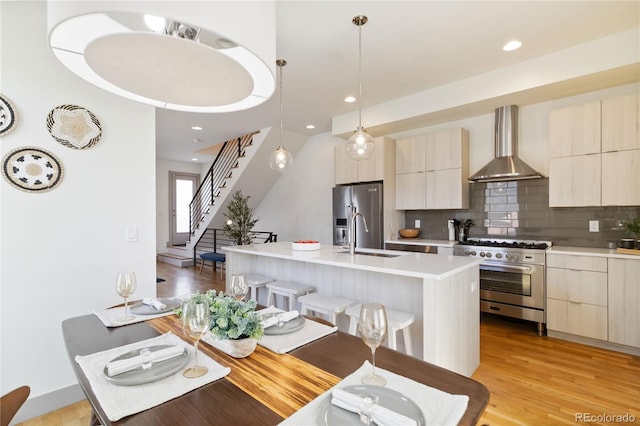 2409 Court Pl, Denver, CO 80205 - kitchen with backsplash, appliances with stainless steel finishes, modern cabinets, and wall chimney exhaust hood