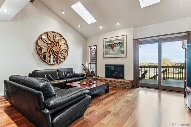 living room featuring high vaulted ceiling, wood finished floors, recessed lighting, a skylight, and a brick fireplace