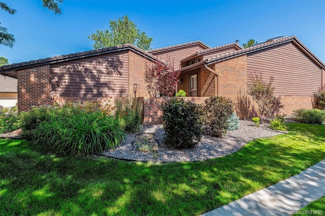 view of side of property with brick siding and a yard