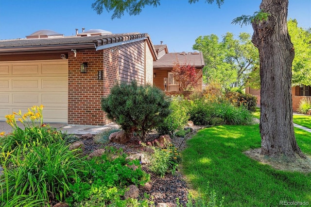 exterior space featuring a garage, brick siding, and a yard