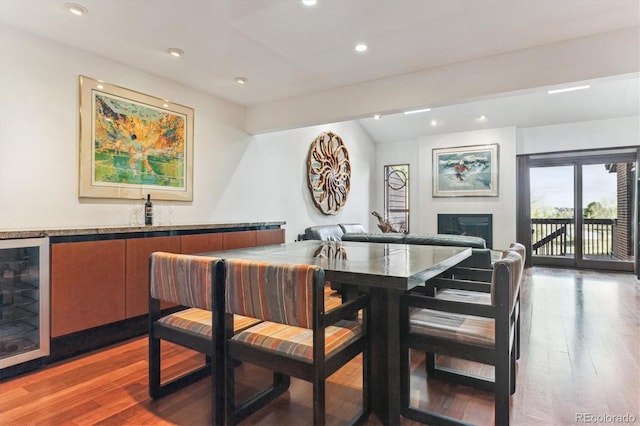 dining space with beverage cooler, wood finished floors, recessed lighting, a fireplace, and wet bar