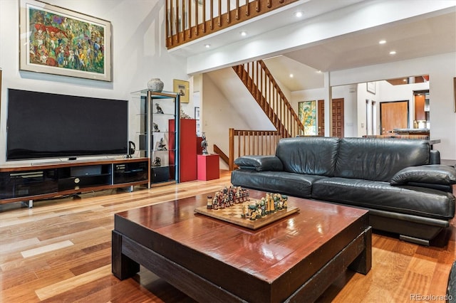 living room with recessed lighting, stairway, wood finished floors, and a towering ceiling