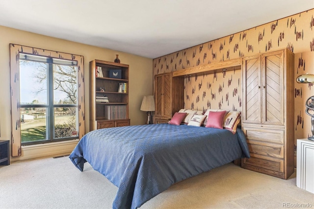 carpeted bedroom featuring wallpapered walls, multiple windows, and visible vents