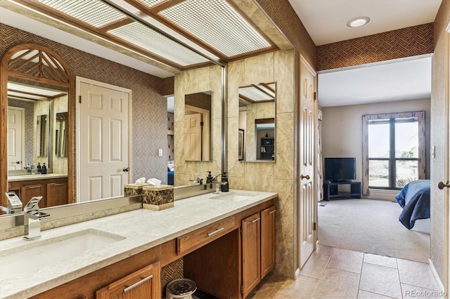 bathroom with double vanity, ensuite bathroom, and a sink