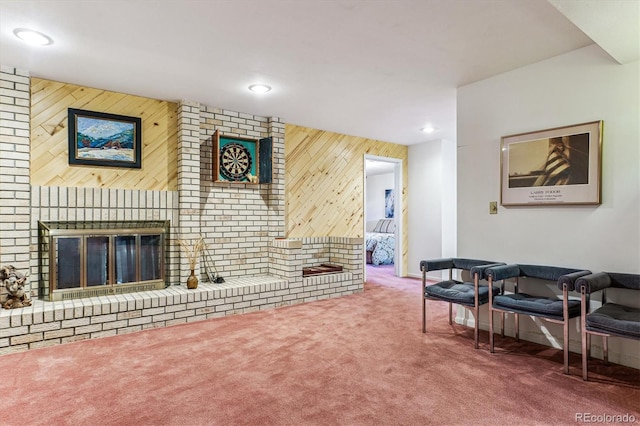 living area with recessed lighting, wood walls, a brick fireplace, and carpet floors