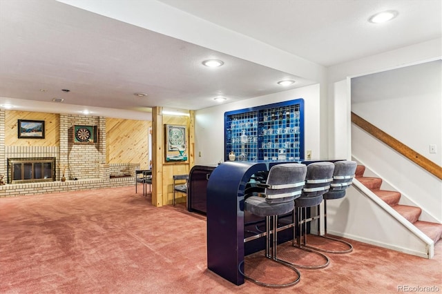 bar featuring carpet flooring, wood walls, a fireplace, and a bar