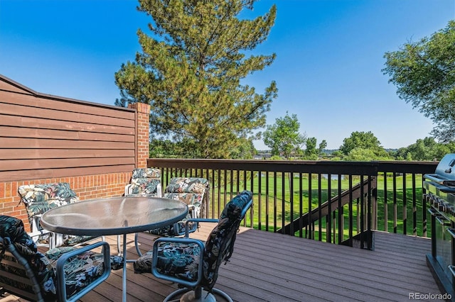 wooden deck with outdoor dining space and a lawn