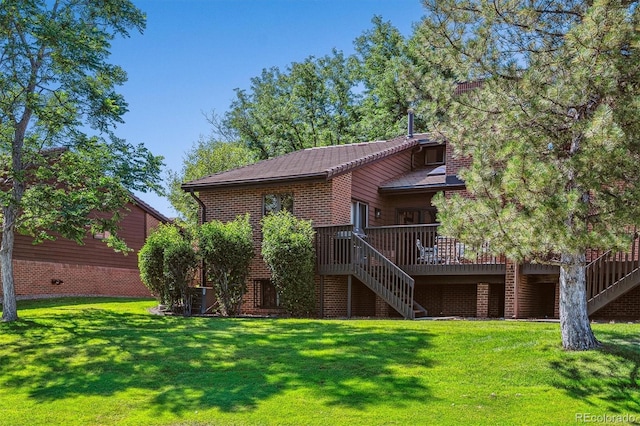 rear view of property featuring stairway, a lawn, a deck, and brick siding