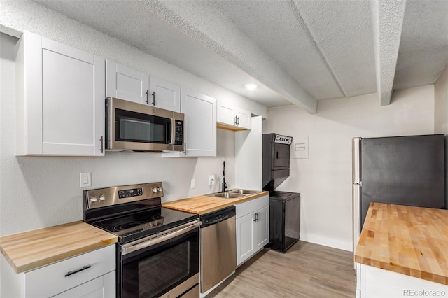 kitchen featuring white cabinetry, stainless steel appliances, and wood counters