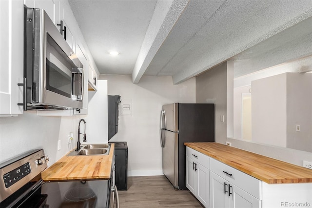 kitchen featuring wooden counters, appliances with stainless steel finishes, sink, light hardwood / wood-style flooring, and white cabinets