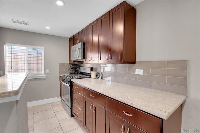 kitchen with tasteful backsplash, light stone counters, stainless steel appliances, and light tile patterned flooring