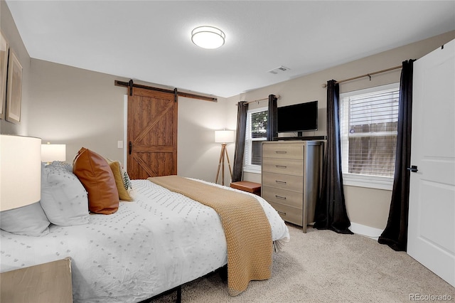 bedroom with a barn door and light carpet