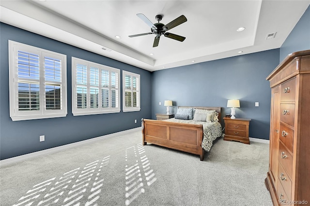 bedroom featuring light colored carpet, ceiling fan, and a raised ceiling