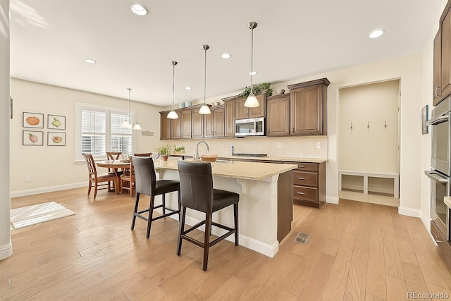 14672 Melco Ave, Parker, CO 80134 - kitchen featuring stainless steel appliances, light wood-style flooring, a breakfast bar, a sink, and recessed lighting