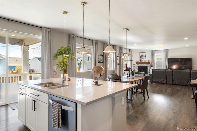 kitchen with a fireplace, white cabinetry, pendant lighting, sink, and a kitchen island with sink